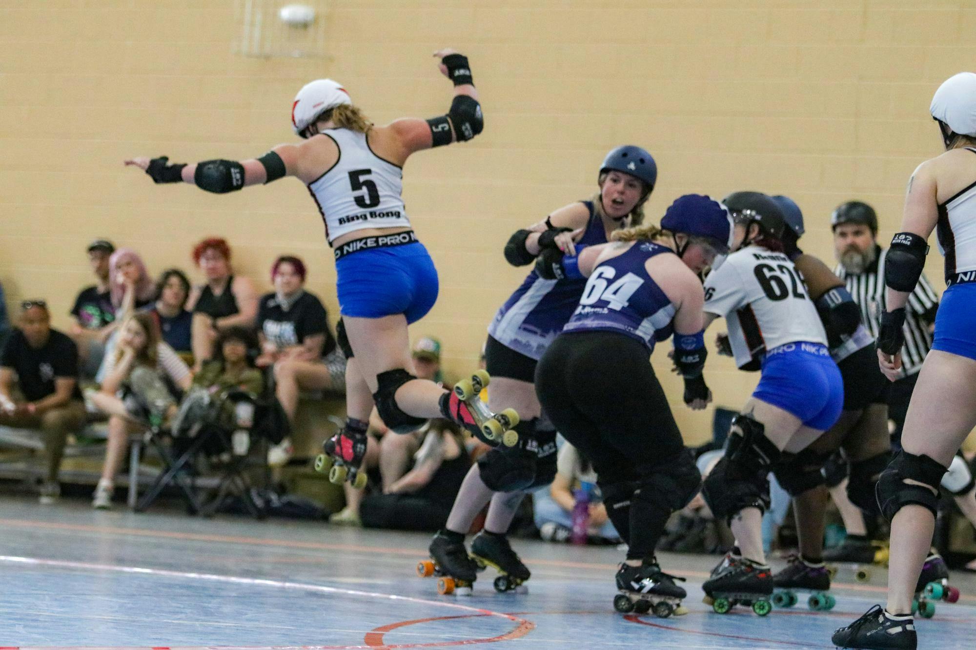 Columbia Roller Derby skater Darby “Bing Bong” MacDonald jumps over the infield and around opposing Chattanooga All Star blockers at St. Andrews Park on March 21, 2026. The jump is an “apex jump,” which allows a skater to cut the inside of the track by jumping over it. “I was wondering if they were going to hit me down again, and they didn’t,” MacDonald said.