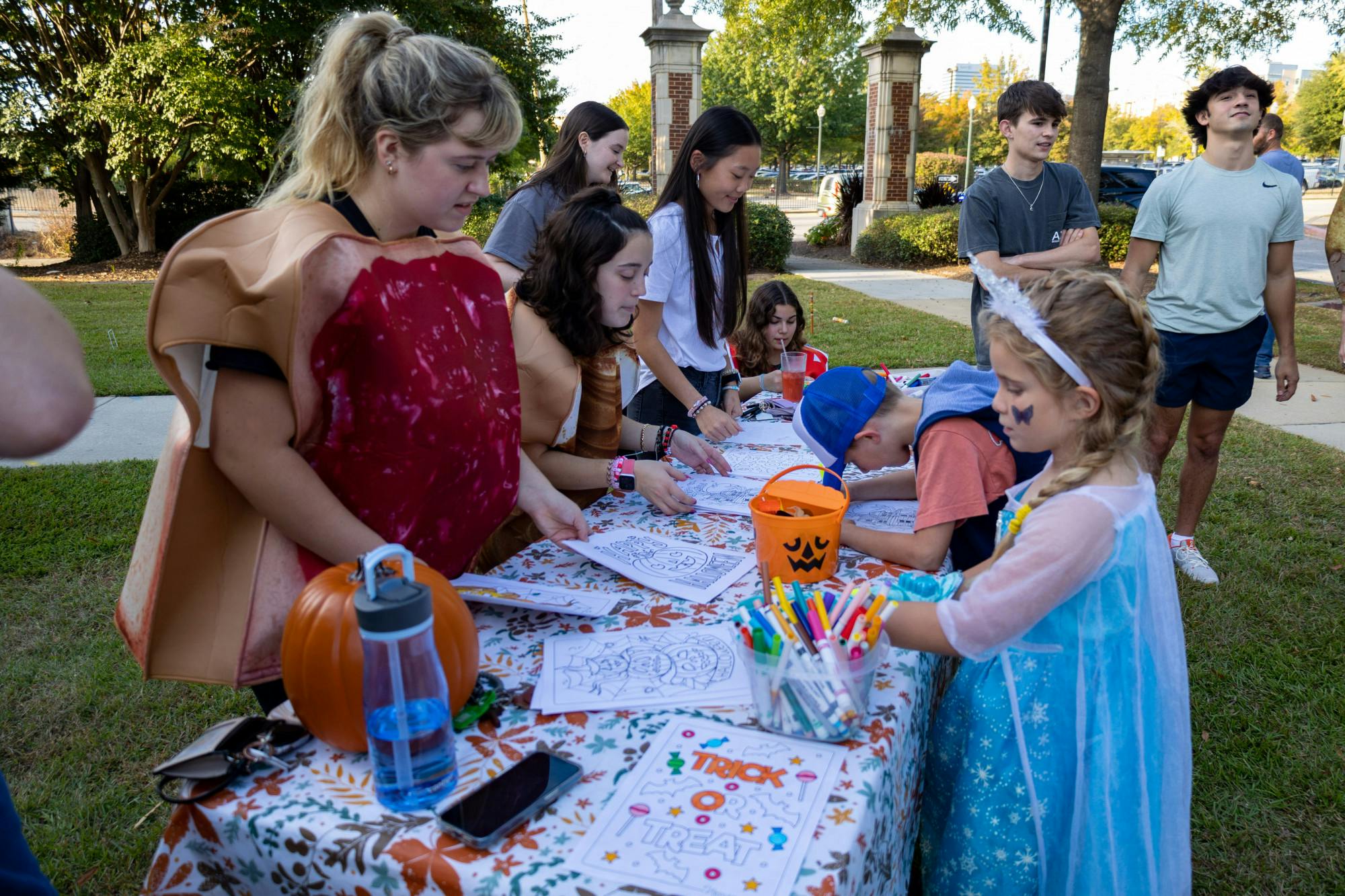 A young girl in a princess costume draws on a coloring sheet at one of the Trick or Treat with the Greeks' activity tables on Oct. 25, 2022. USC Greek fraternities and sororities welcomed community members to Greek Village for an evening of games, fun activities, unity and trick or treating.