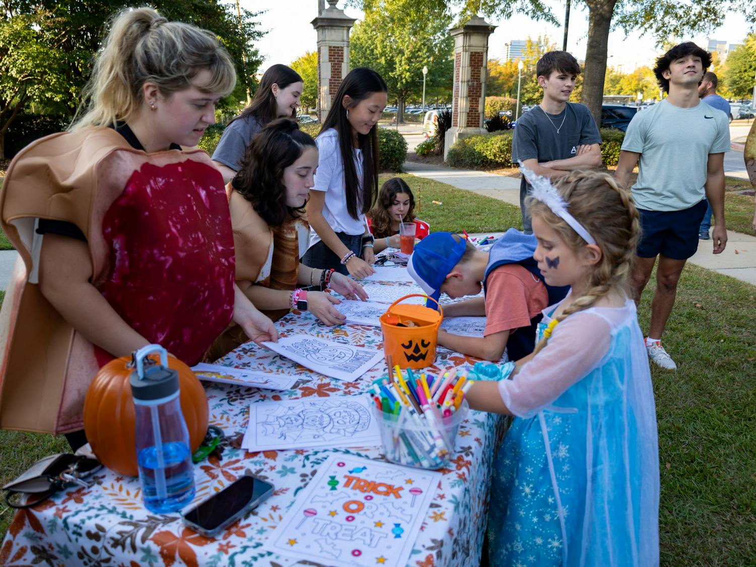 A young girl in a princess costume draws on a coloring sheet at one of the Trick or Treat with the Greeks' activity tables on Oct. 25, 2022. USC Greek fraternities and sororities welcomed community members to Greek Village for an evening of games, fun activities, unity and trick or treating.