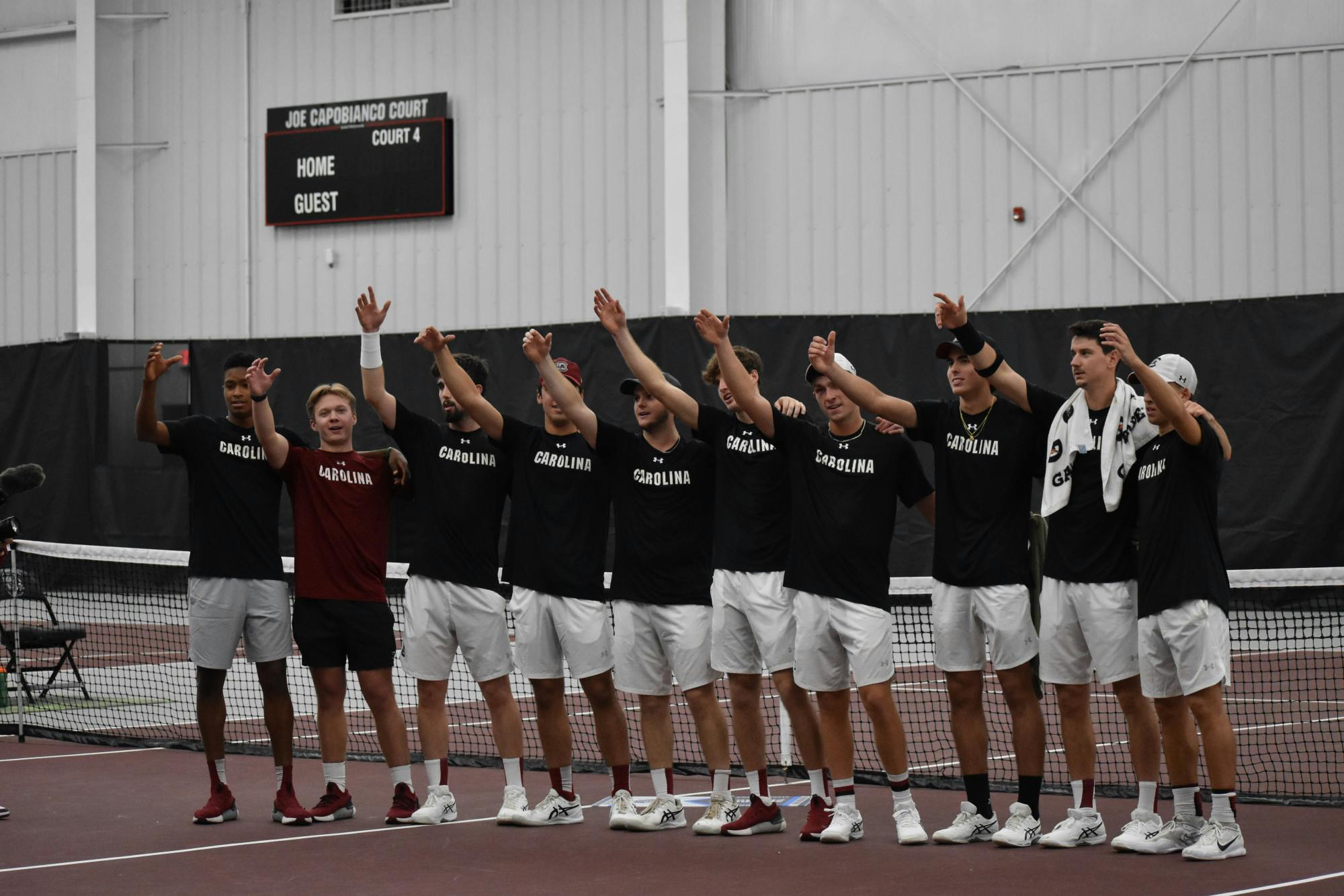 The South Carolina men’s tennis team stand together with an arm raised as the university's alma mater plays on day two of the ITA Kickoff Weekend event at the Carolina Indoor Tennis Center on Jan. 29, 2023. The South Carolina Gamecocks beat N.C. State 4-0, making it the winner of the ITA tournament.&nbsp;