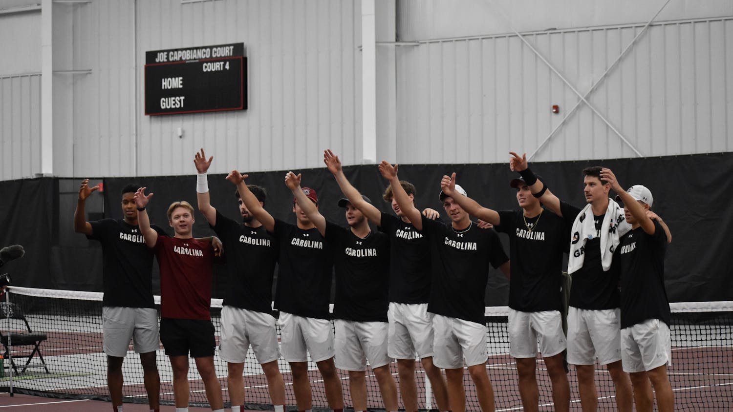 The South Carolina men’s tennis team stand together with an arm raised as the university's alma mater plays on day two of the ITA Kickoff Weekend event at the Carolina Indoor Tennis Center on Jan. 29, 2023. The South Carolina Gamecocks beat N.C. State 4-0, making it the winner of the ITA tournament.&nbsp;