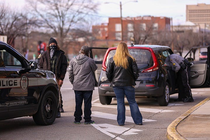 A group waits while their car is searched on the Assembly Street side of the Statehouse following the “Drive4America” rally. It is unknown whether the group was let go or not. &nbsp;