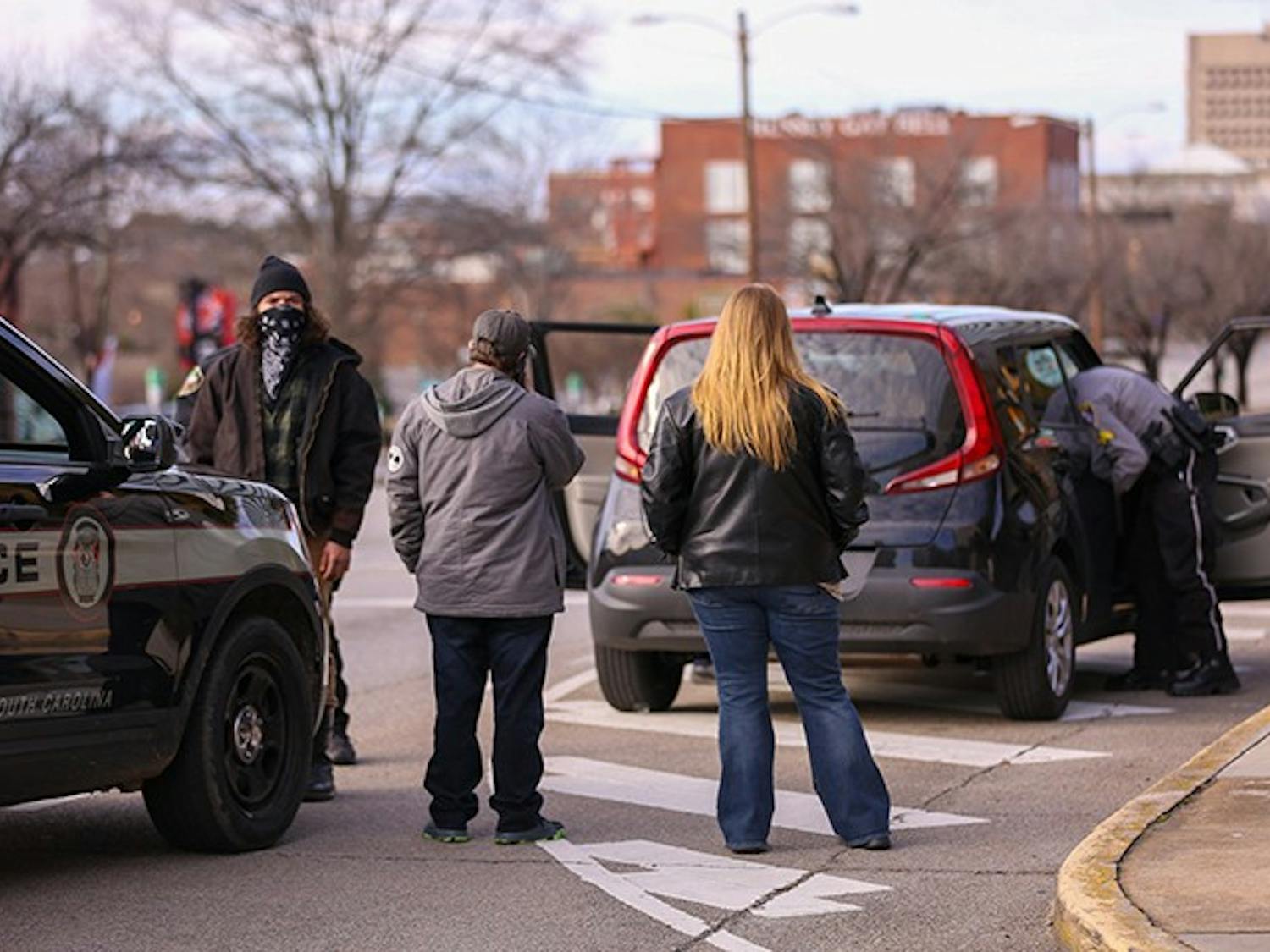 A group waits while their car is searched on the Assembly Street side of the Statehouse following the “Drive4America” rally. It is unknown whether the group was let go or not. &nbsp;
