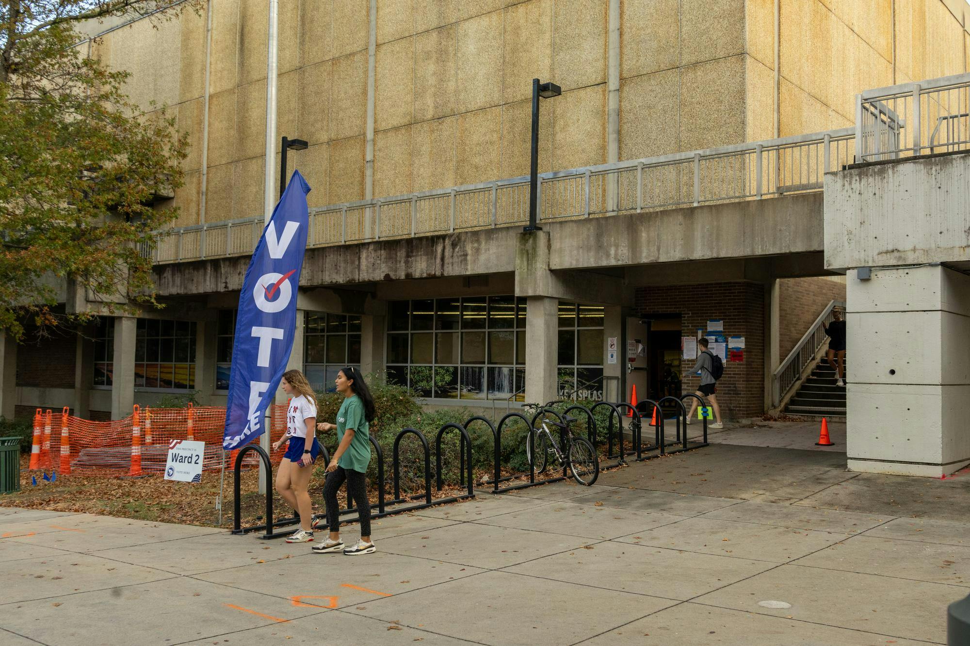 Two girls walk past a blue flag that has "VOTE" written on it at the Blatt PE Center on Nov. 5, 2024. Blatt PE Center served as the voting location for Precinct 2.