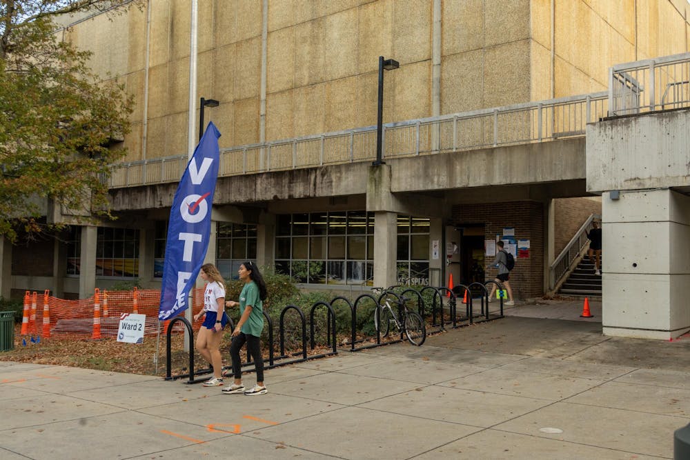 <p>Two girls walk past a blue flag that has "VOTE" written on it at the Blatt PE Center on Nov. 5, 2024. Blatt PE Center served as the voting location for Precinct 2.</p>