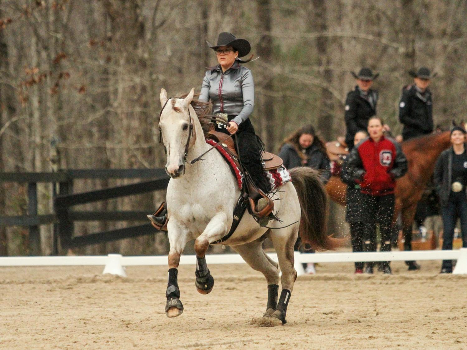 Senior Claire Pound, mounted on Paddy, demonstrates the pattern for the reigning category during the meet against Texas A&amp;M at One Wood Farm on Feb. 11, 2023. Pound is superstitious about what she wears when gearing up to compete. “I always wear the same jewelry. I have a ring that I always have to wear in the same spot. I wear it on my right thumb every single time I show,” Pound said.&nbsp;