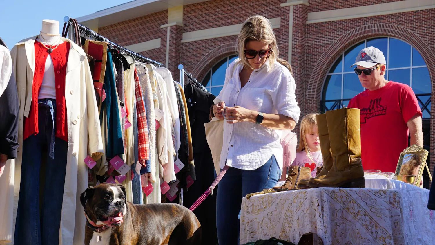 Columbia resident Ashley Floyd and her dog Aliza look through clothing at Bullseye Vintage market in front of Segra Park on Nov. 16, 2025. The event is hosted by the team behind Soda City Market and will add new antique and vintage vendors to the market every third Sunday.