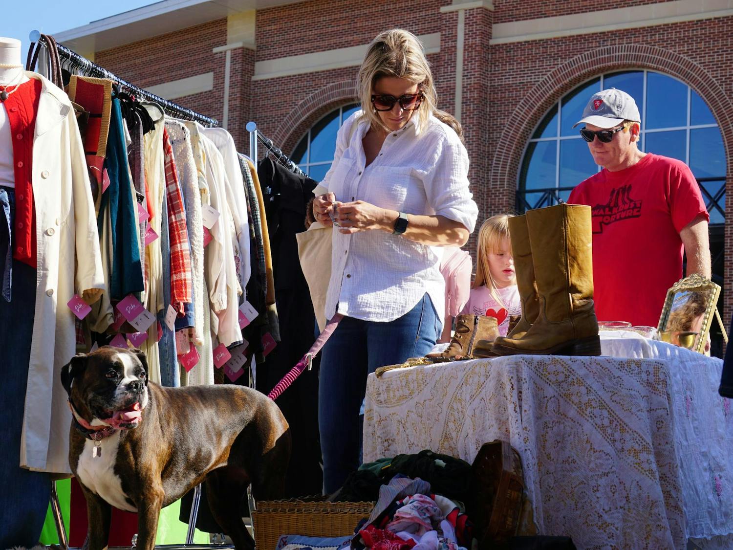 Columbia resident Ashley Floyd and her dog Aliza look through clothing at Bullseye Vintage market in front of Segra Park on Nov. 16, 2025. The event is hosted by the team behind Soda City Market and will add new antique and vintage vendors to the market every third Sunday.