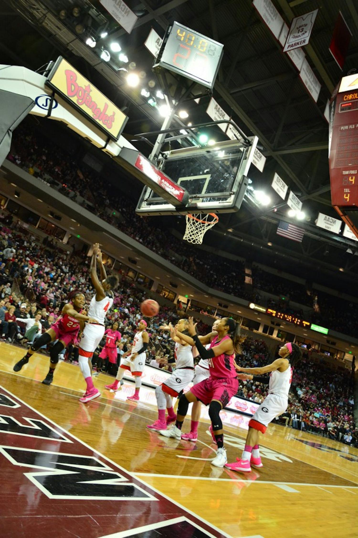 Lady Gamecock Sarah Imovbioh (24) passes to teammate Alaina Coates (41) as the game erupts into adrenaline and chaos in only the opening minutes of the first quarter. South Carolina Gamecocks vs Georgia Bulldogs. Colonial Life Arena, Columbia, SC. February 18, 2016
