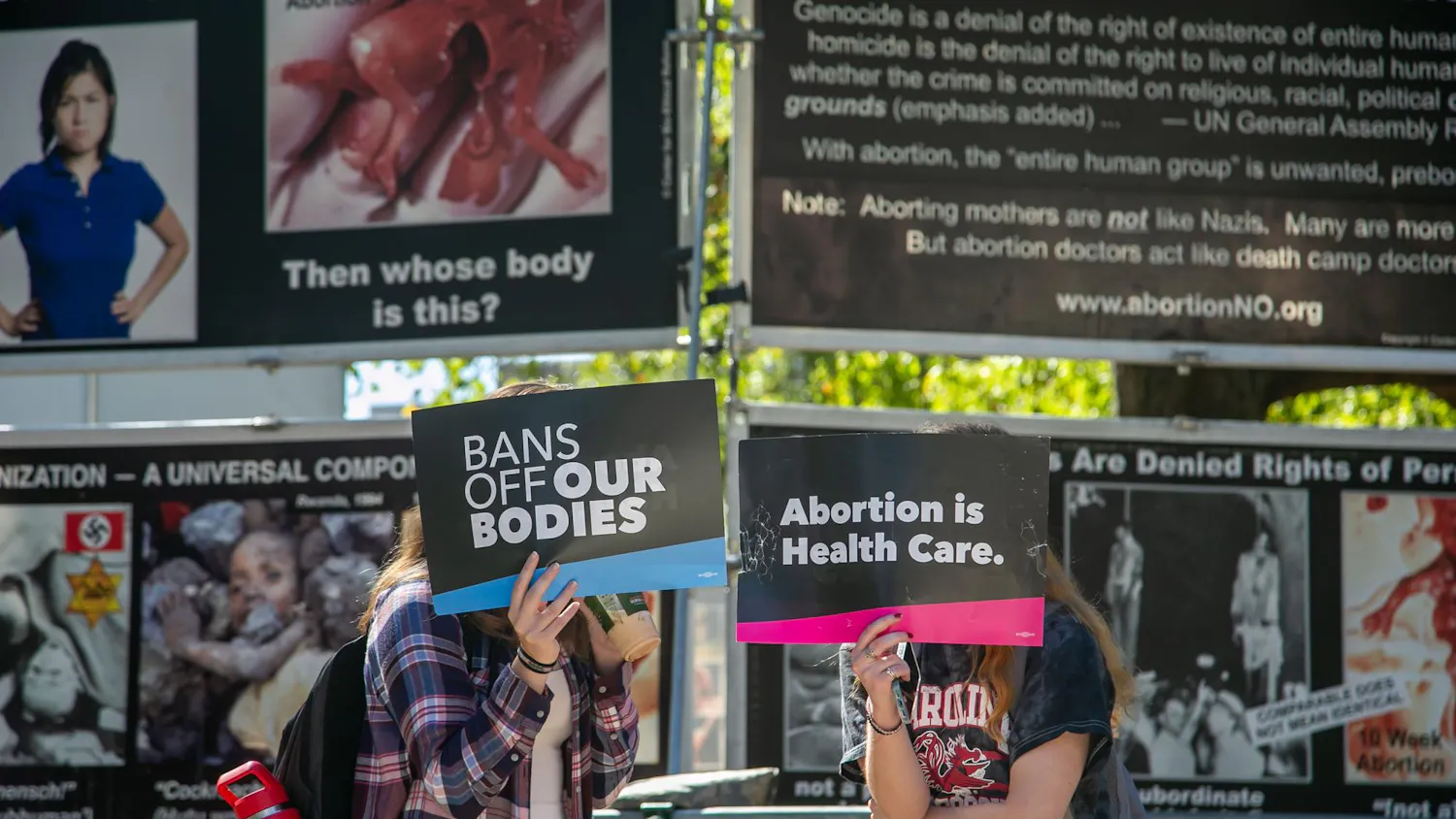 Two protesters hide their faces from media during a counterprotest of the Genocide Awareness Project's display on the University of South Carolina campus on Oct. 22, 2024. Over the course of two days, the display was set up on Greene Street and Davis Field next to the Russell House Student Union.