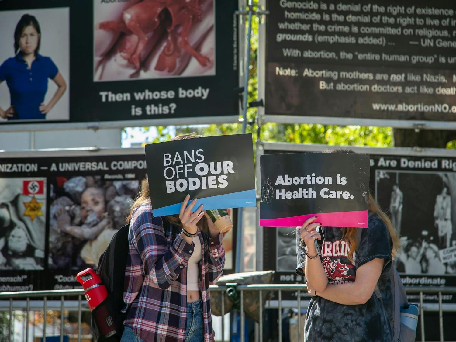 Two protesters hide their faces from media during a counterprotest of the Genocide Awareness Project's display on the University of South Carolina campus on Oct. 22, 2024. Over the course of two days, the display was set up on Greene Street and Davis Field next to the Russell House Student Union.