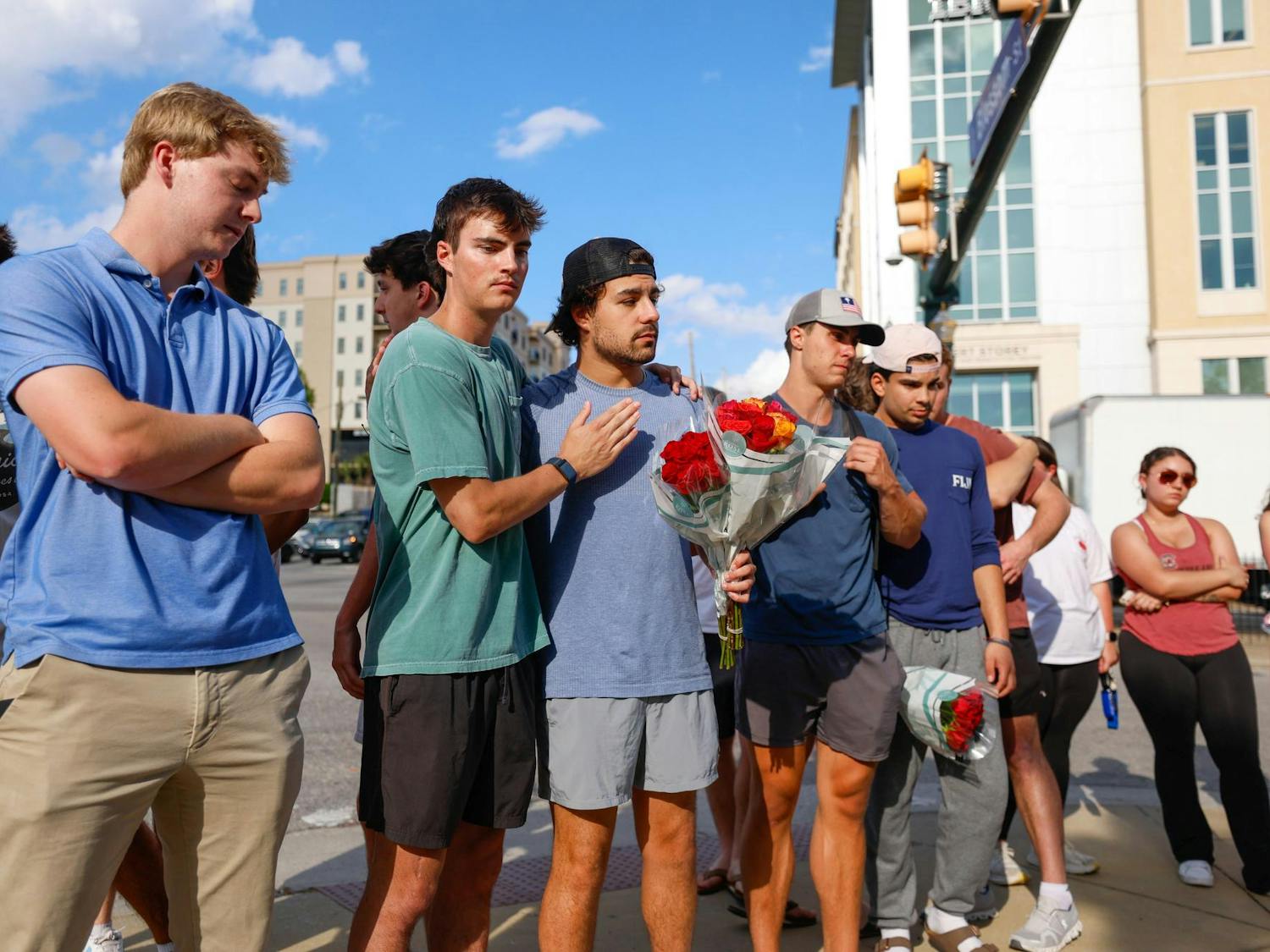 A group of students stand at the intersection of Assembly and Blossom streets to leave flowers at the memorial for Nathaniel "Nate" Baker on April 3, 2025. Baker was a third-year business student who was struck and killed by a pickup truck the previous day.