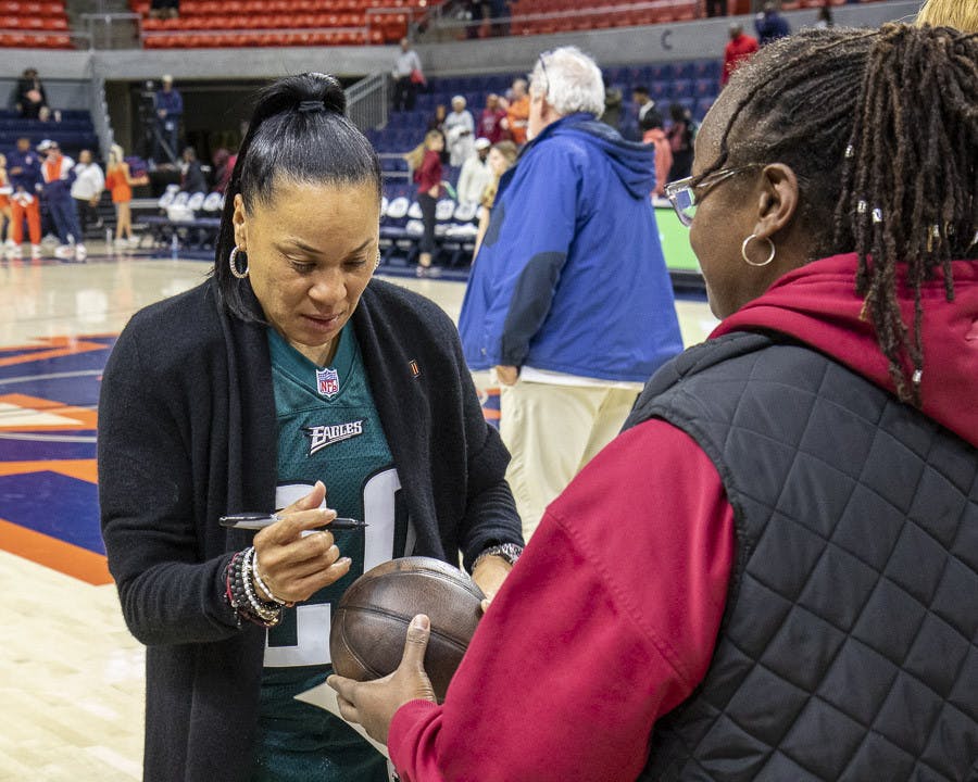 Head coach Dawn Staley signs a fan's basketball after the team's victory against Auburn on Feb. 9, 2023. This marks the Gamecocks' 30th win, setting a new program record.&nbsp;