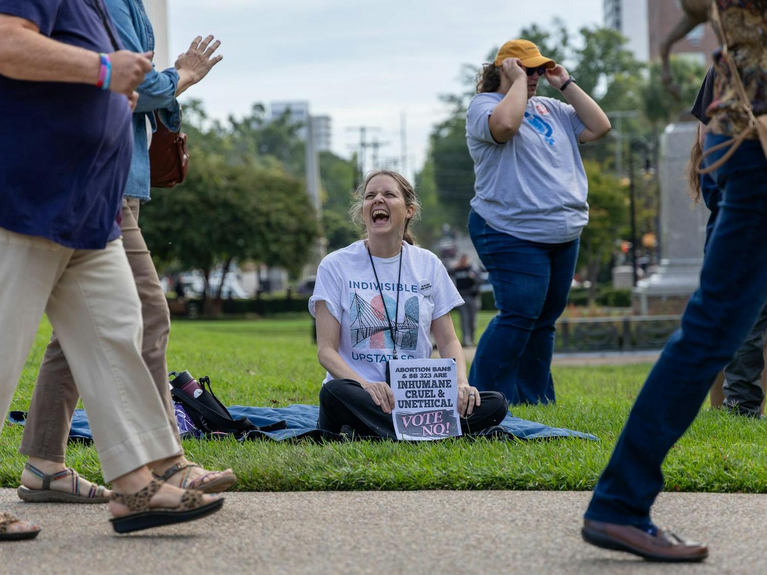 A woman smiles while sitting on the lawn of the Statehouse during a protest against a proposed abortion bill on Oct. 1, 2025. Public commentary lasted from 9 p.m. to 1 p.m., and a line formed outside the Gressette Building where the hearing took place.