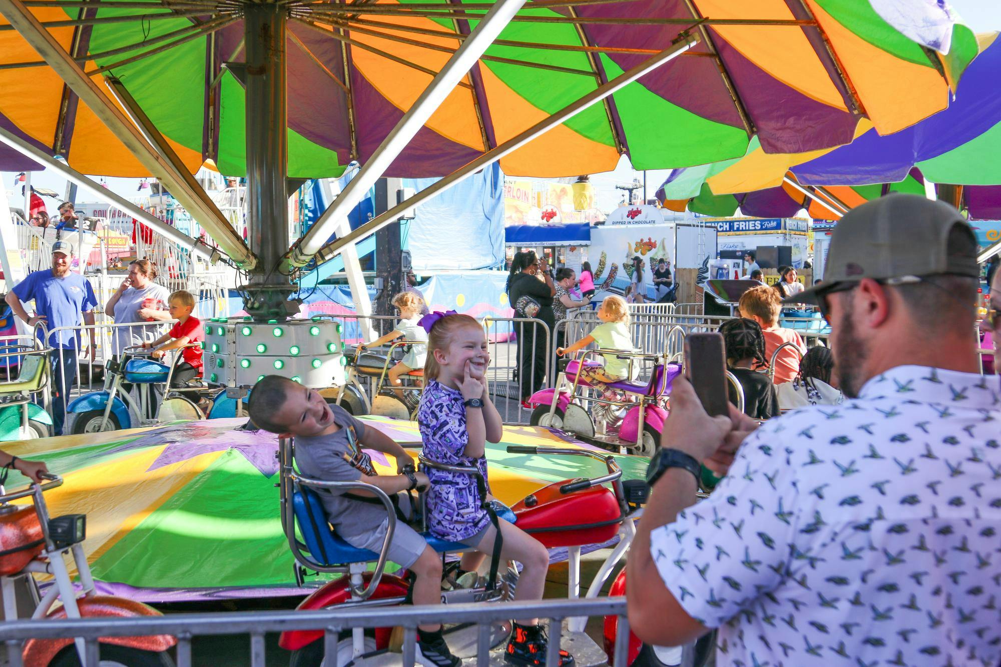 A father takes a photo of his children riding a merry-go-round-style ride at the South Carolina State Fair on Oct. 13, 2025. The fair ran from Oct. 8 to 19 at the state fairgrounds on Rosewood Drive.