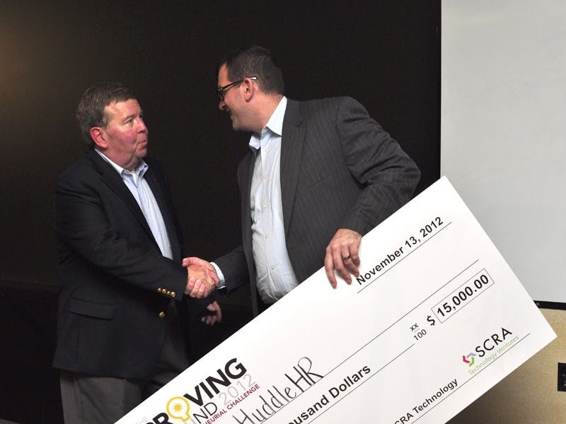 Sean Rankin (right) accepts a $15,000 prize for his business concept, HuddleHR.