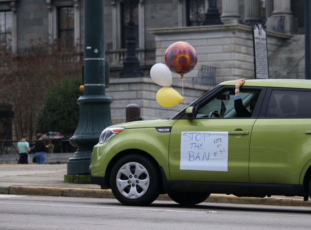 <p>The lead car in the "Stop the Ban" caravan circles the Statehouse while honking its horn and holding signs protesting the abortion legislation.&nbsp;</p>