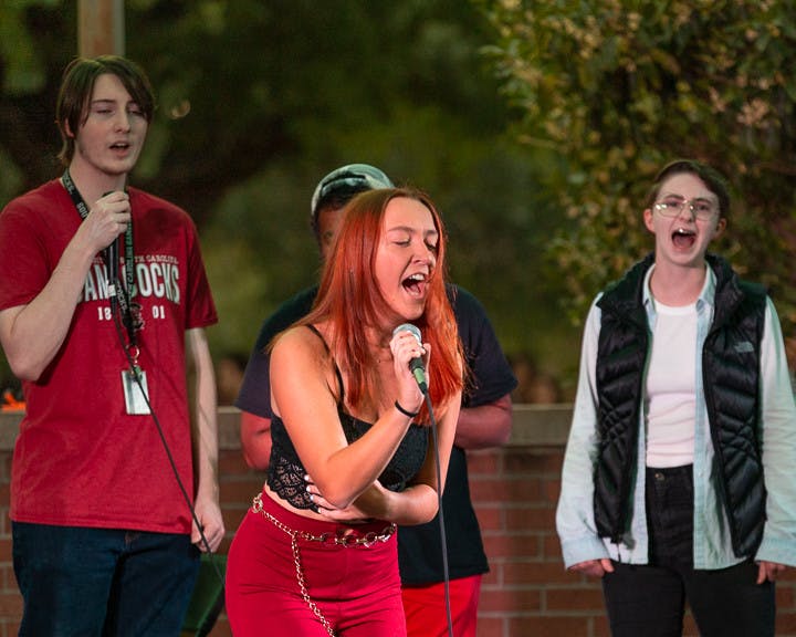 Third-year psychology student Erin McDonough sings with the background choir during The Resonance's performance at the USC Battle of the Bands on Oct. 5, 2022. The competition, brought acappella, folk, rap and rock music to the Russell House Patio in a variety of performances.