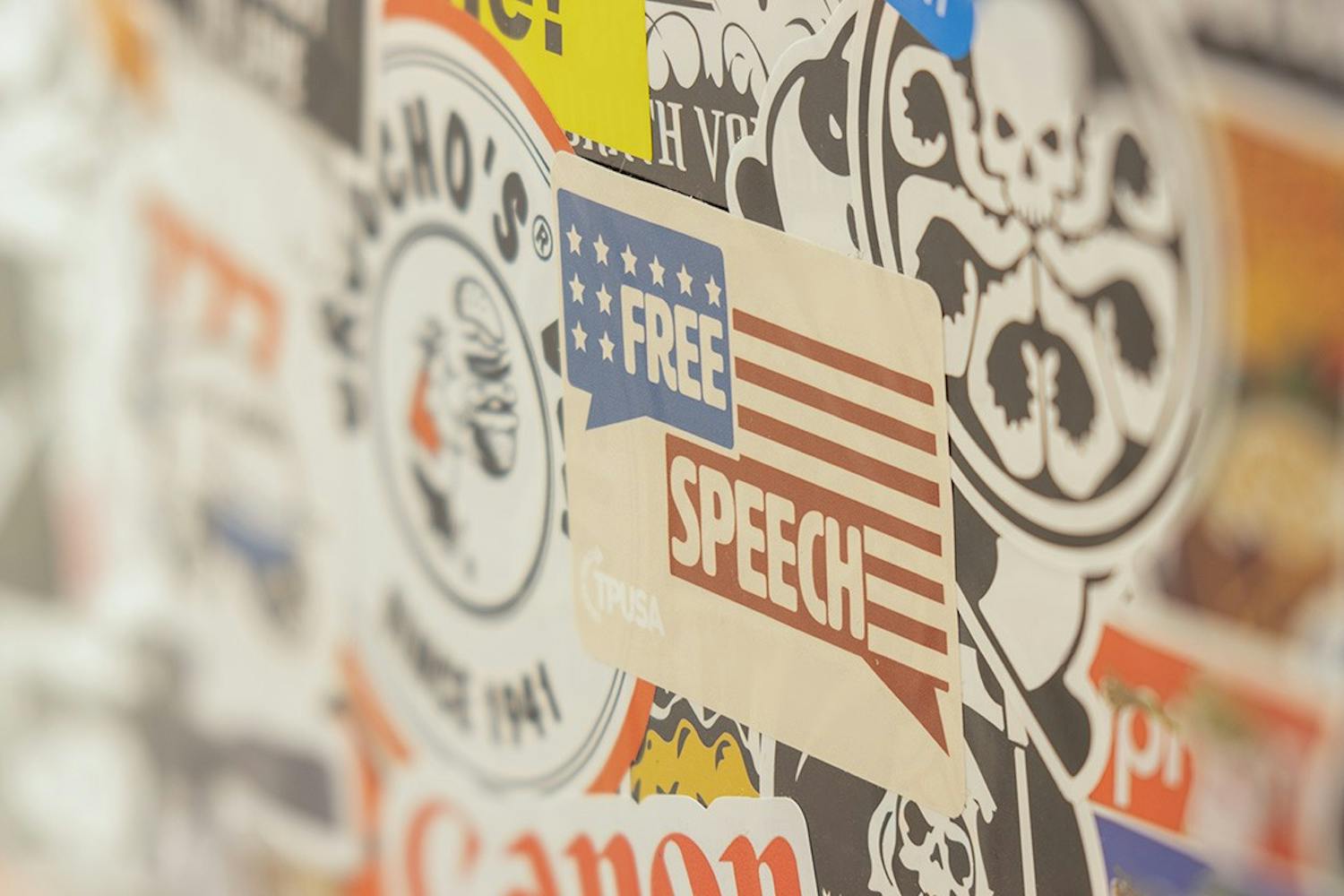 A Turning Point USA "Free Speech" sticker on the top layer of a sticker bomb.