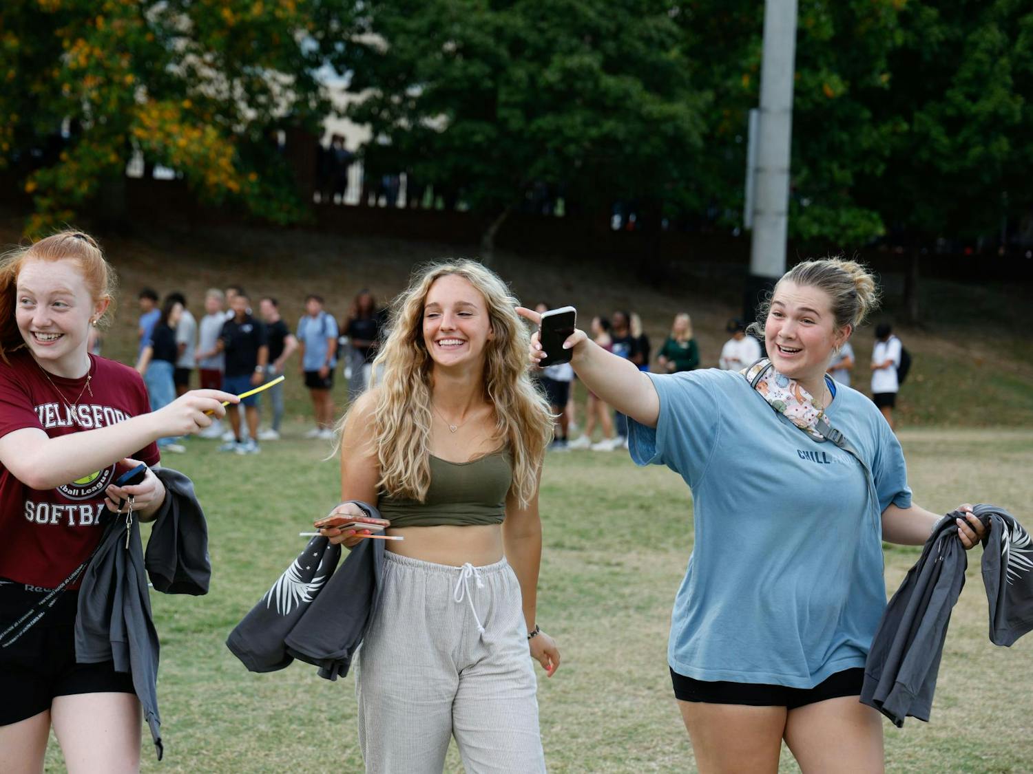 Three students walk around Blatt field smiling and pointing on Sept. 18, 2024. Students that attended received a free t-shirt.