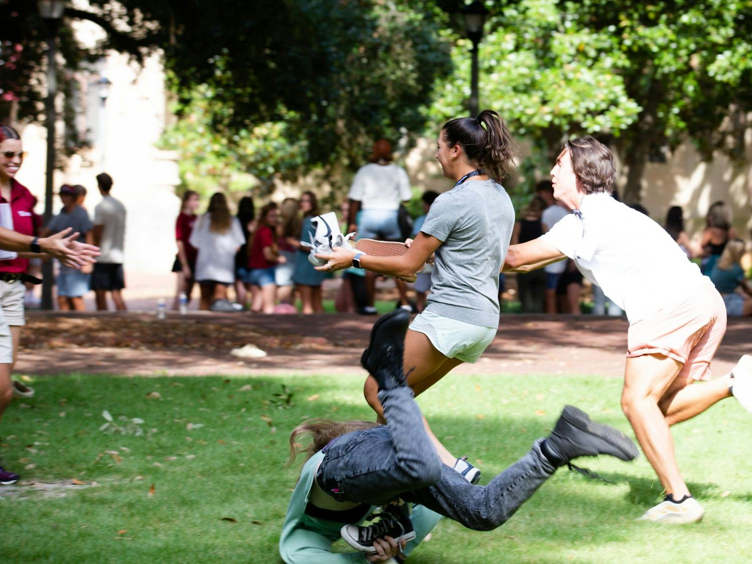 A first-year student falls as her fellow group members sprint to give their orientation leader a shoe during an orientation session on July 20, 2022. This game is played during orientation sessions throughout the summer to help new students have fun and make friends before starting their freshman year in the fall.&nbsp;