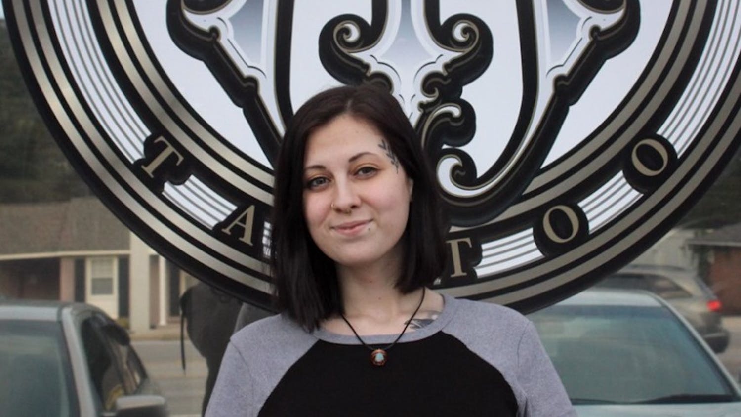 Tattoo artist at Magnetizm Tattoo Heather Belle stands in front of the shop. Magnetizm Tattoo is located at 7345 Parklane Road, Unit C.