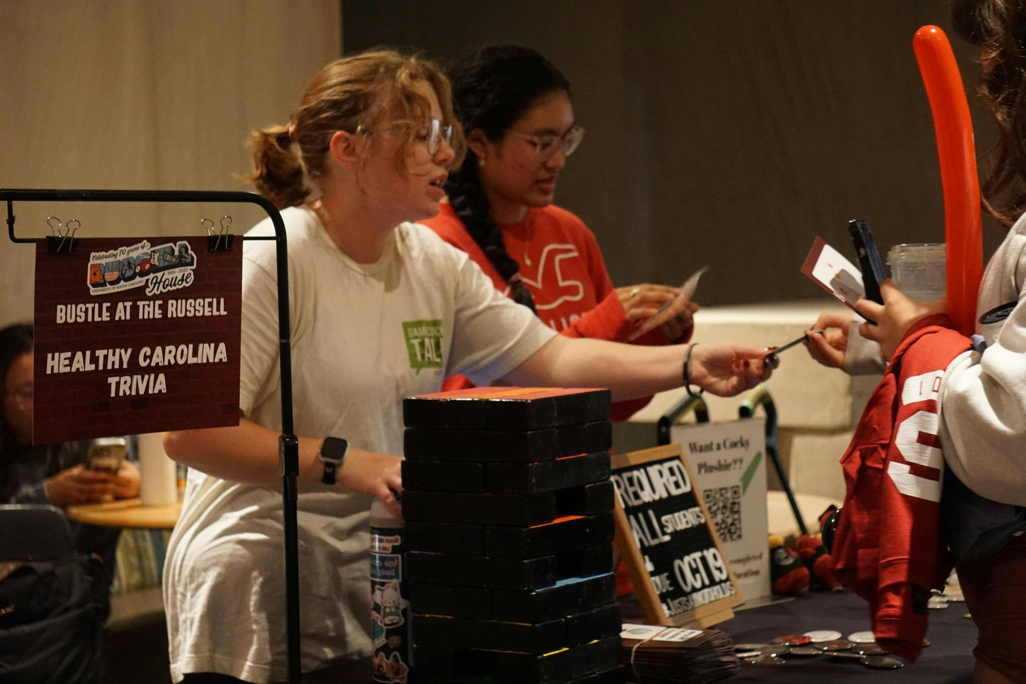 Fourth-year psychology student Kate Willis scans students' CarolinaCards so they can participate in Healthy Carolina Trivia during Bustle at the Russell on Oct. 16, 2025, in the Russell House. Multiple activities were held throughout the celebration of the Russell House being a center of student life for 70 years, including karaoke, a video game truck and roller skating.