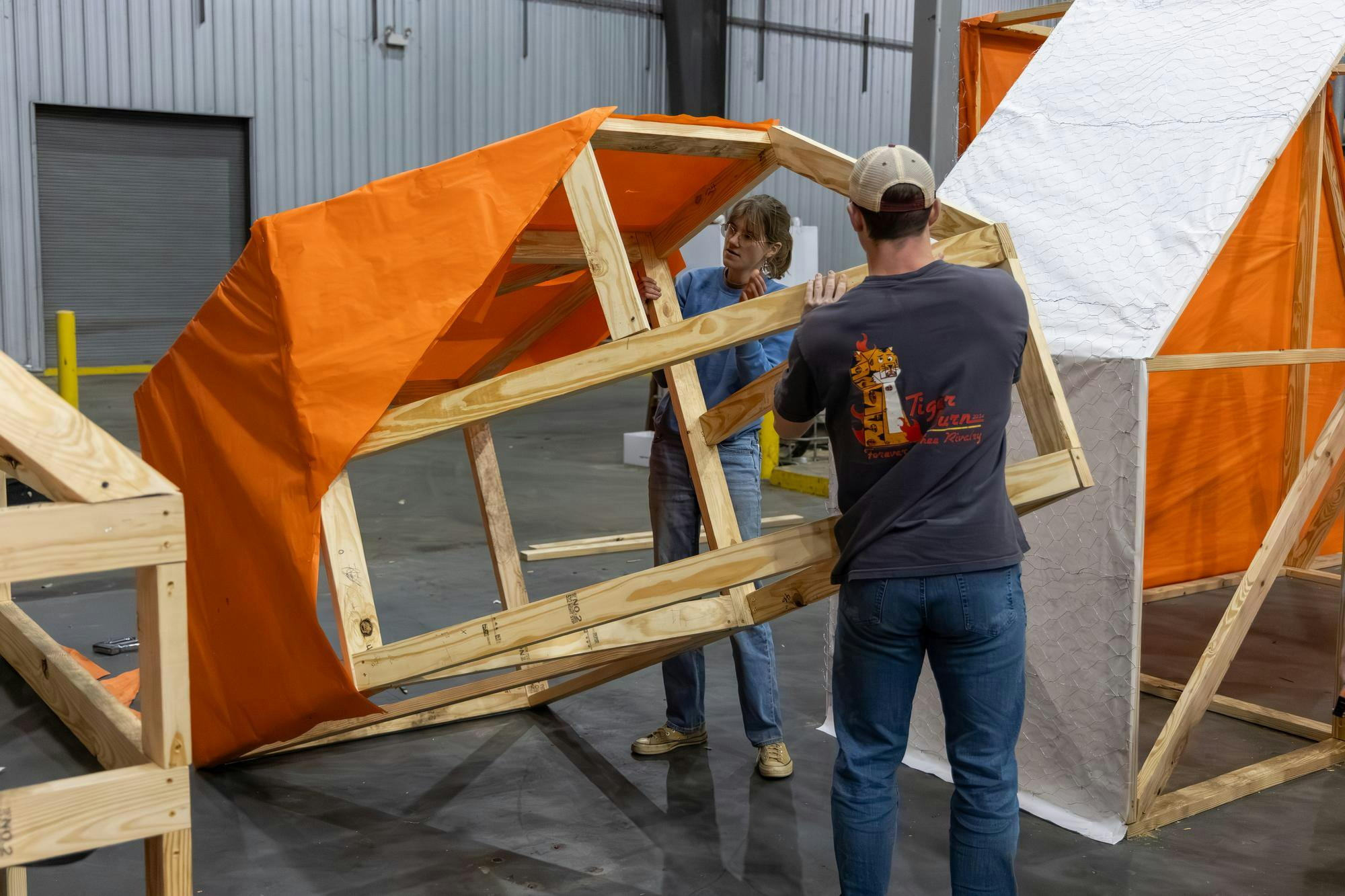 Third-year civil engineering student Jordan Henderson (left) and second-year biomedical engineering student Connor Prince (right) rotate a portion of the Tiger Burn statue on Nov. 10, 2025. Each section has an outer lining of orange paper, which is then reinforced by a layer of mesh wiring.