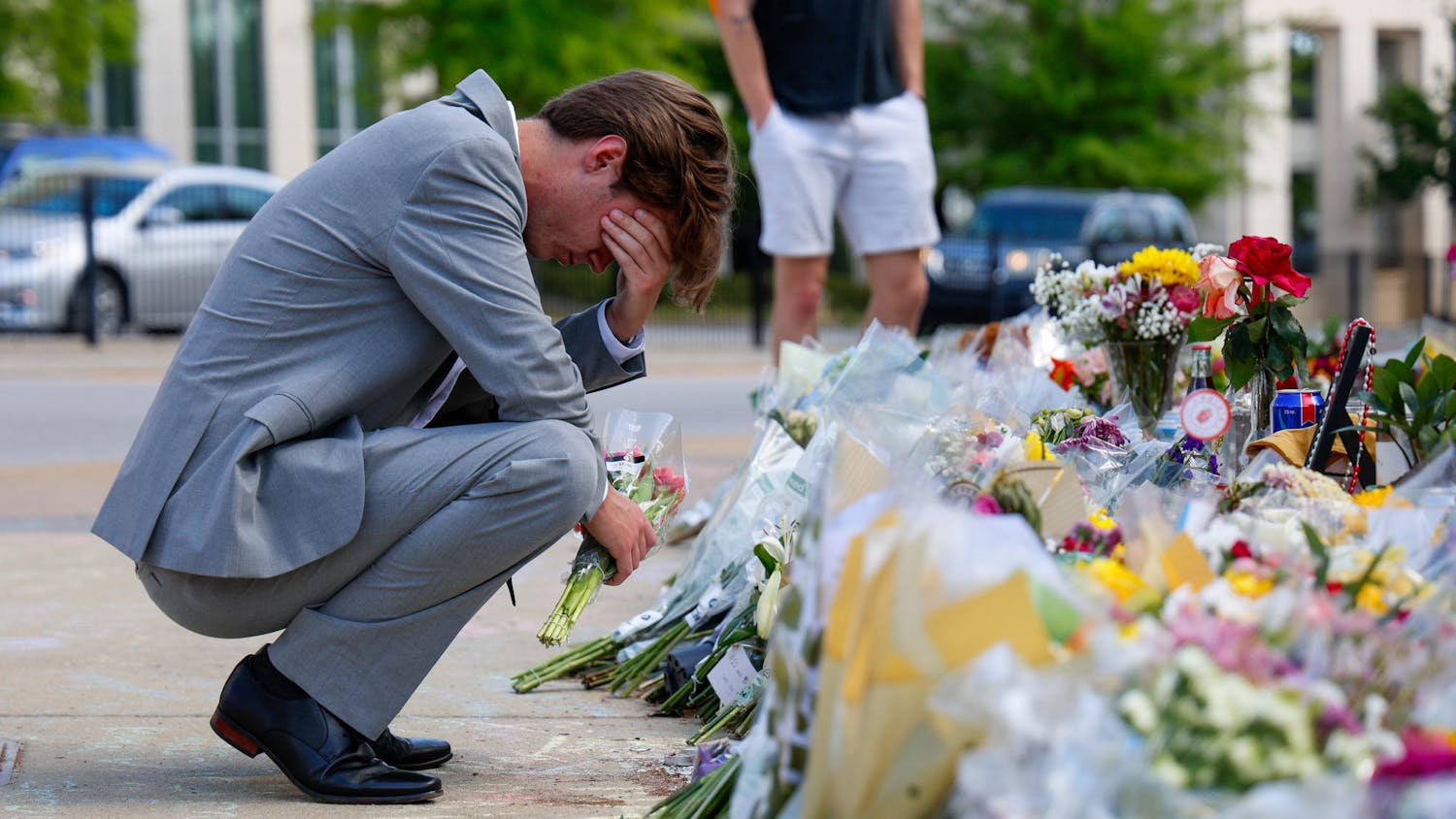 A student holds his hand to his face while kneeling at the memorial for Nathaniel Baker at Strom Thurmond Wellness and Fitness Center on April 5, 2025. Hundreds of students left flowers and other keepsakes at the site in memory of Baker.