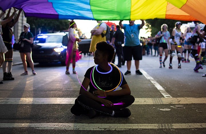 One of the attendees sits underneath a large pride flag before the South Carolina pride parade on Friday.
