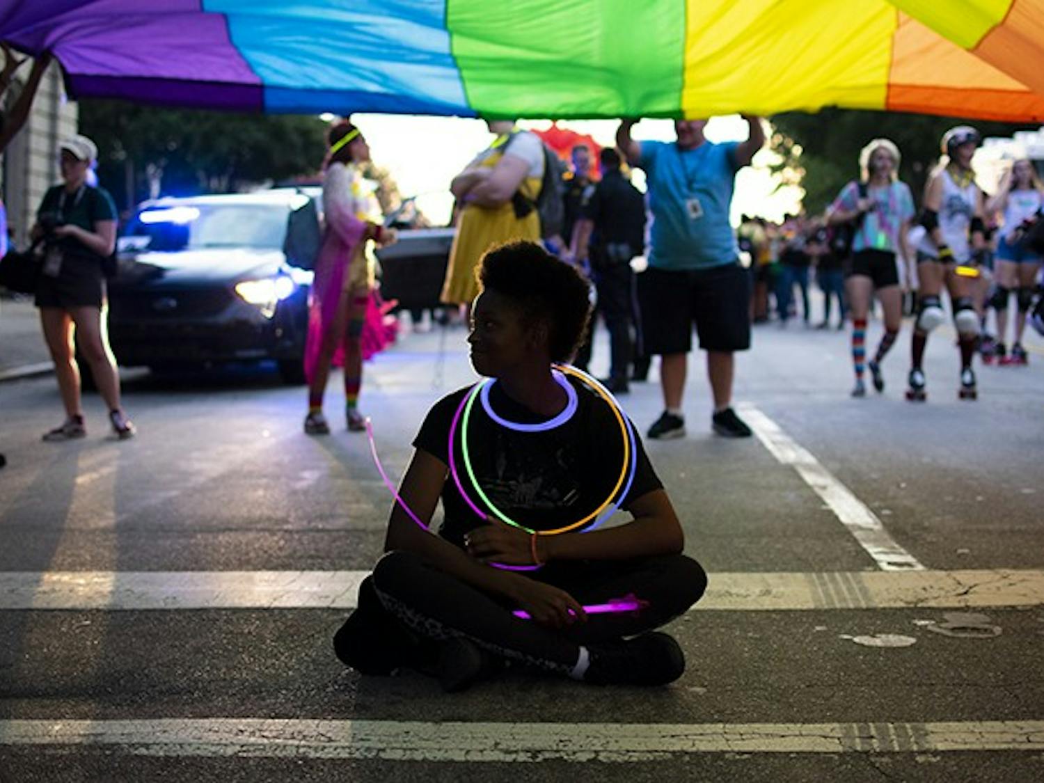 One of the attendees sits underneath a large pride flag before the South Carolina pride parade on Friday.