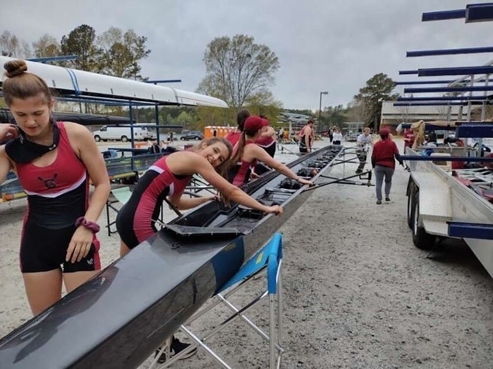 <p>Junior Hannah Skerkis, senior Gabby Ricche, and freshman Alex Defalco preparing their boat for the Women's Novice Four. The Gamecock Rowing Club took to the water at the Clemson Regatta in Clemson, S.C. on April 1, 2022.</p>