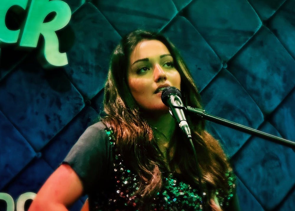 <p>Fourth-year student artist Farah "Camille" Shahida sings at Hard Rock Cafe, D.C. Shahida channels her love of music to unite people and create a sense of community through her performances.</p>