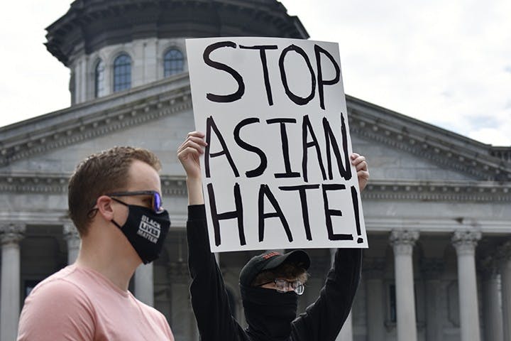 A protestor displays a sign that reads “STOP ASIAN HATE” in front of the State House on March 7, 2021.