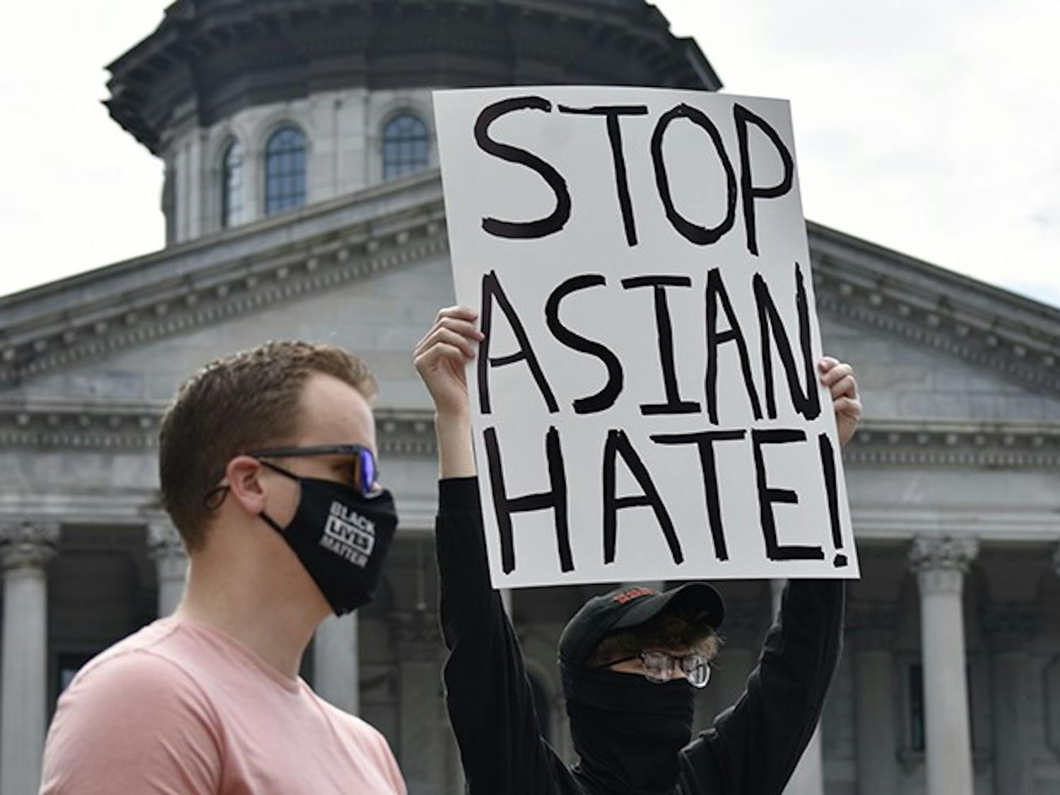 A protestor displays a sign that reads “STOP ASIAN HATE” in front of the State House on March 7, 2021.