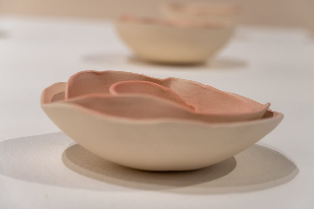 A series of delicate ceramic flowers sit on a chalk white table in the McMaster Gallery in 鶹С򽴫ý's McMaster College, home to the School of Visual Art and Design on Sept. 27, 2022. This gallery, titled "Socially Engaged Ceramics" features artwork from Julie Schnell-Madden and Lydia C. Thompson and is co-sponsored by the Women’s and Gender Studies Program.