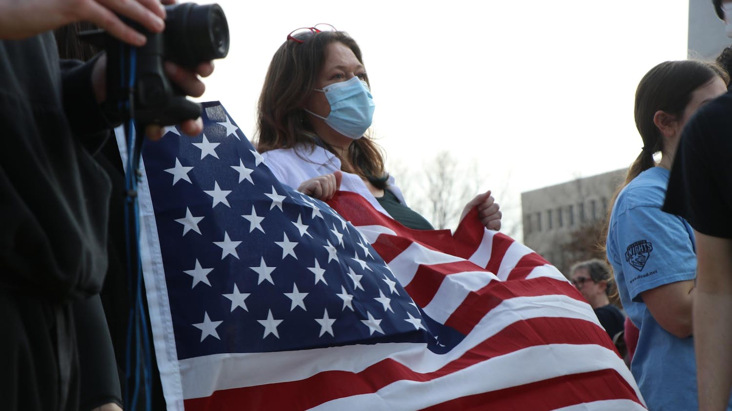 A protestor holding the American flag listening to speakers at the Statehouse on Feb. 5, 2025. Protestors were rallying against the Trump administration and Project 2025
