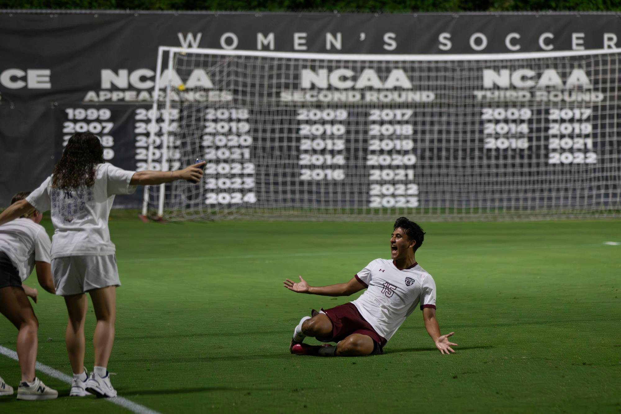 FILE - Sophomore midfielder Alejandro Velazquez-Lopez slides in front of the women’s team to celebrate their win against Queens on Sep. 23, 2025 at Eugene E. Stone III Stadium.