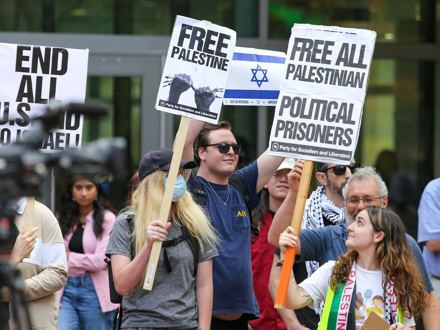 A pro-Israel attendee holds up a sign of the Jewish flag in between pro-Palestinian attendees at a walkout for Palestine on the Russell House Patio on Nov. 9, 2023. More than 10,000 Palestinians and 1,400 Israelis have been killed in the first month of fighting between Hamas and Israel.