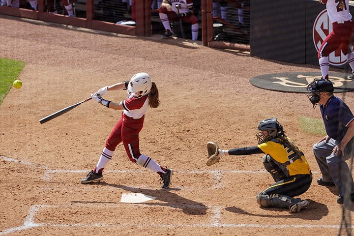 A South Carolina softball player swings the bat at a pitch thrown by the Missouri pitcher.
