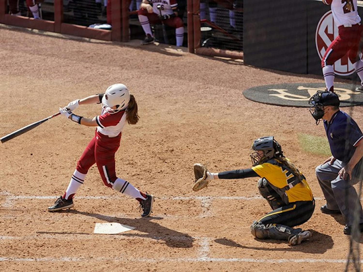 A South Carolina softball player swings the bat at a pitch thrown by the Missouri pitcher.