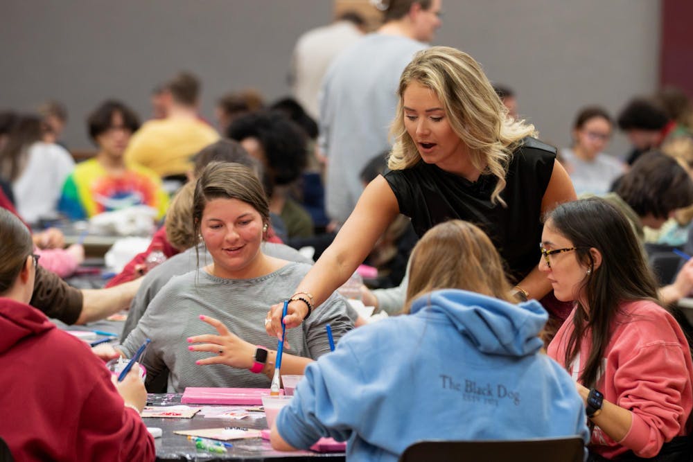 <p>Summer Rogers helps a student during her canvas painting class on Feb. 8, 2024. The free class, hosted by alumna Rodgers, allowed students to create their own USC-themed paintings.</p>