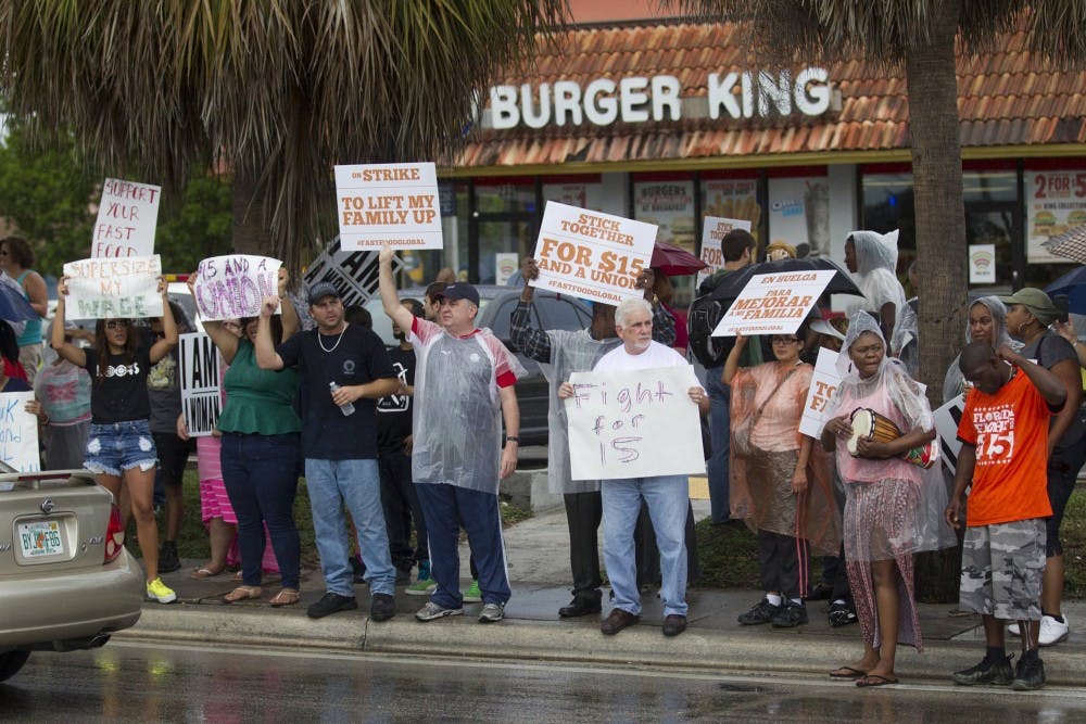 Striking fast food workers hold picket signs as they walk the line in front of restaurants where they picketed during a nationwide protest in favor of a $15/hour minimum wage Sept. 4, 2014 in Miami. In a recent survey, Floridians said they thought minimum wage should be higher. (C.W. Griffin/Miami Herald/TNS) 