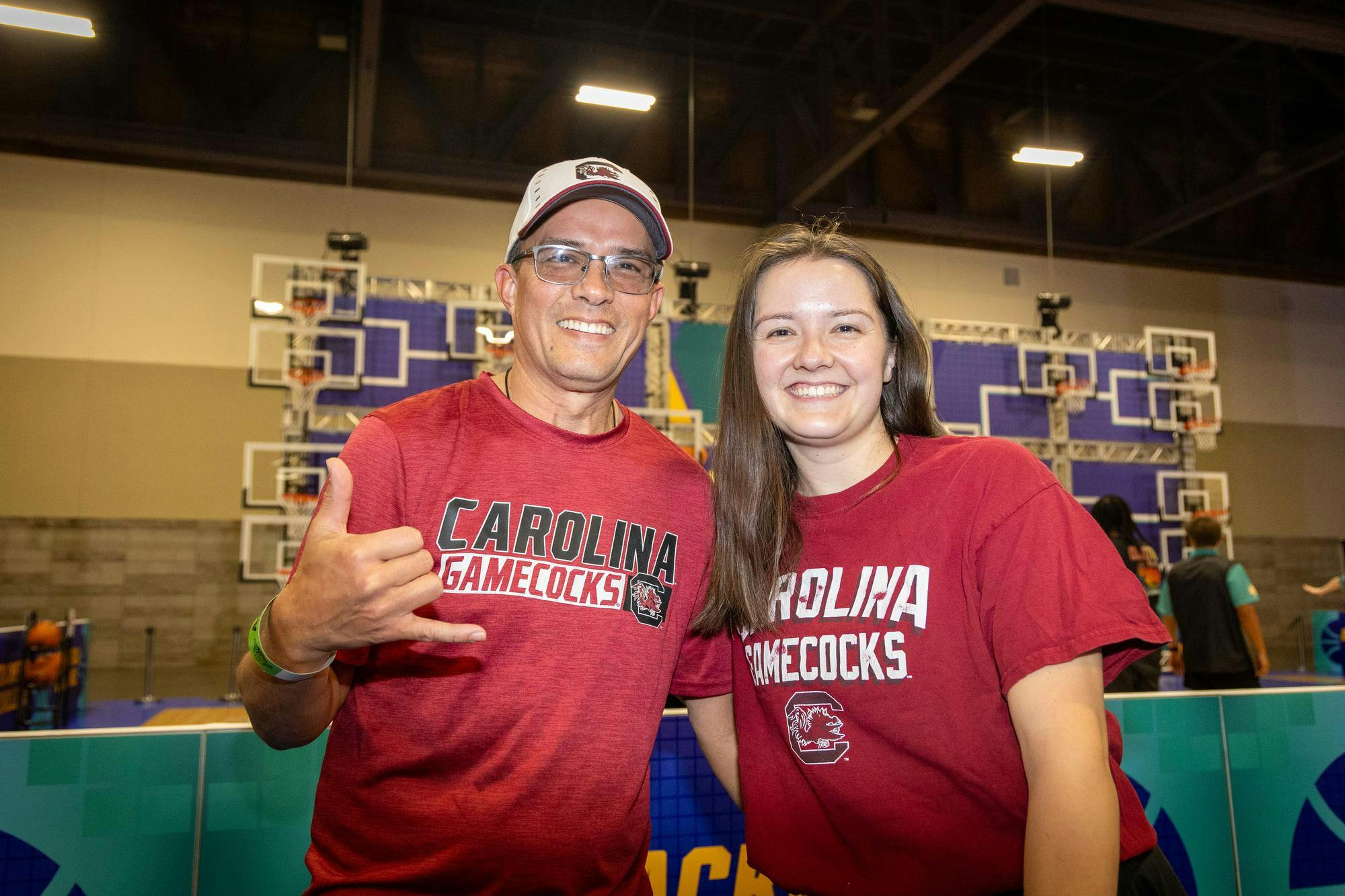 Phoenix, Arizona, resident Kevin Trechsel and Cincinnati, Ohio, resident Juliana Trechsel pose together in front of a basketball game at Tourney Town during March Madness in Phoenix on April 3, 2026. Juliana is a Gamecock alumna who came down to visit family in Phoenix, which Kevin said is a huge spot for all sporting events.