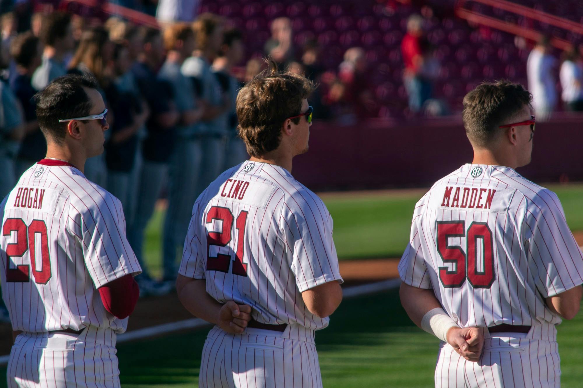 Carolina baseball team members Matt Hogan, Connor Cino, and Kevin Madden salute during the playing of the national anthem on Feb. 18, 2022. The Carolina Gamecocks won the first game in their series against UNCG 9-7.