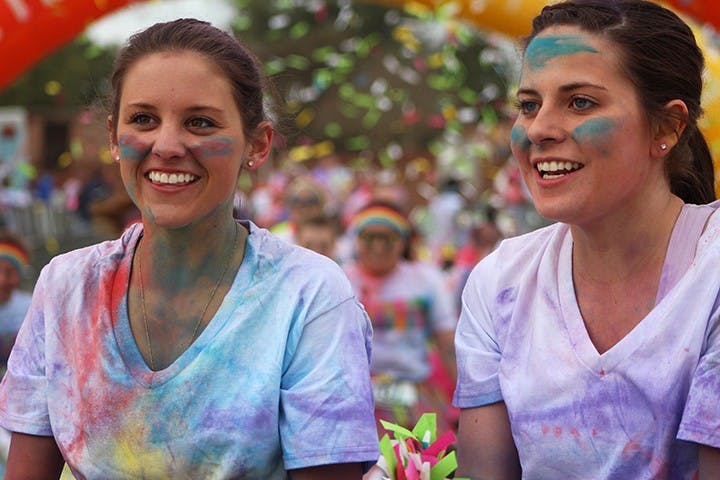 	Covered in color, two girls smile on. 
Heidi Stone/The Daily Gamecock