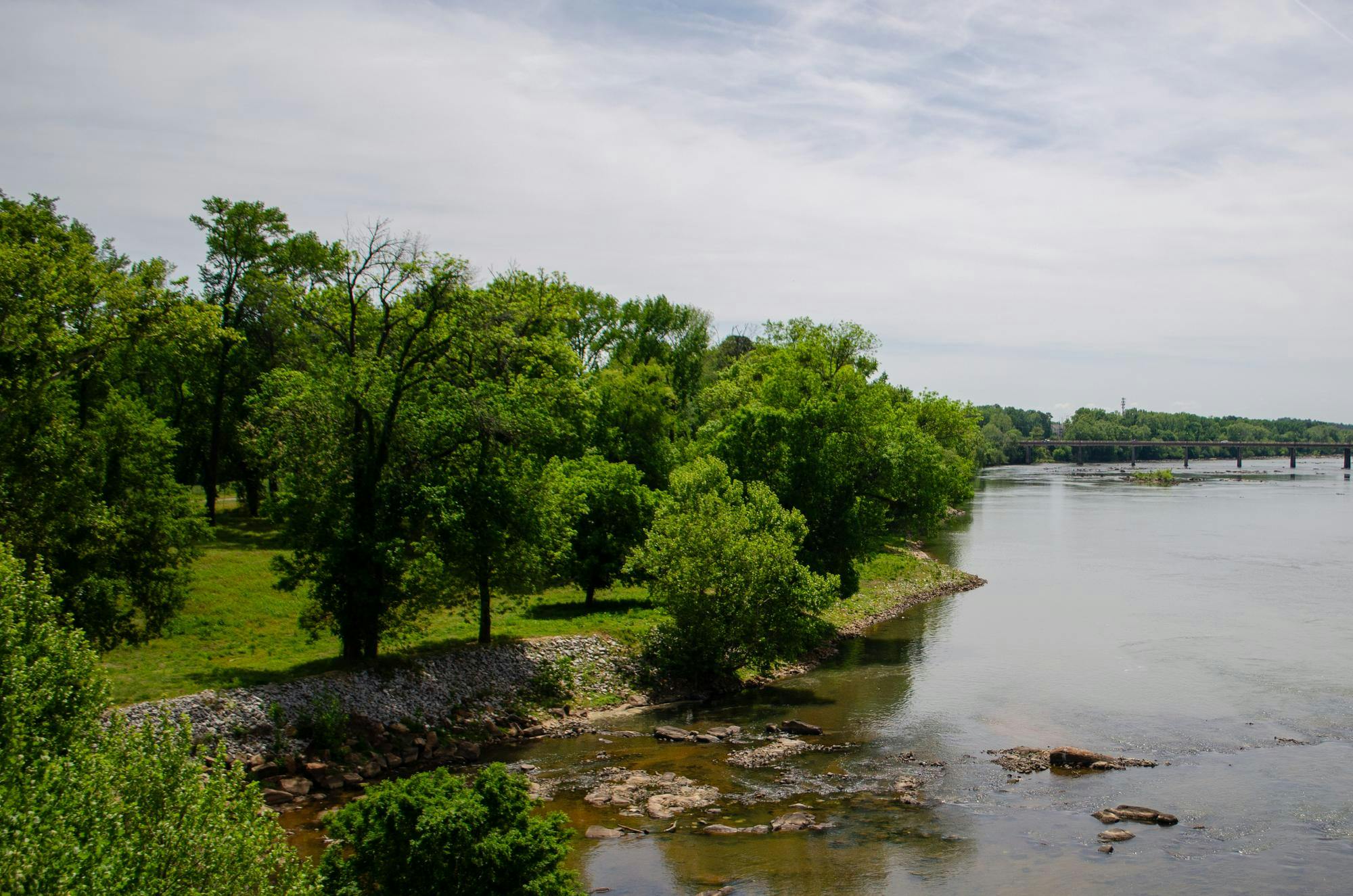 A large, undeveloped section of land by the Congaree River is seen from the Gervais Street bridge on April 13, 2026. The area, currently fenced off, is planned to be developed into a public park.