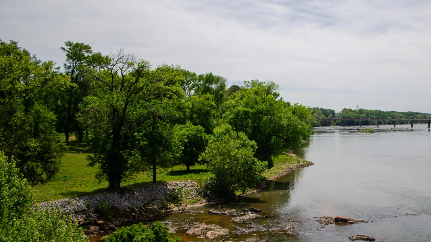 A large, undeveloped section of land by the Congaree River is seen from the Gervais Street bridge on April 13, 2026. The area, currently fenced off, is planned to be developed into a public park.