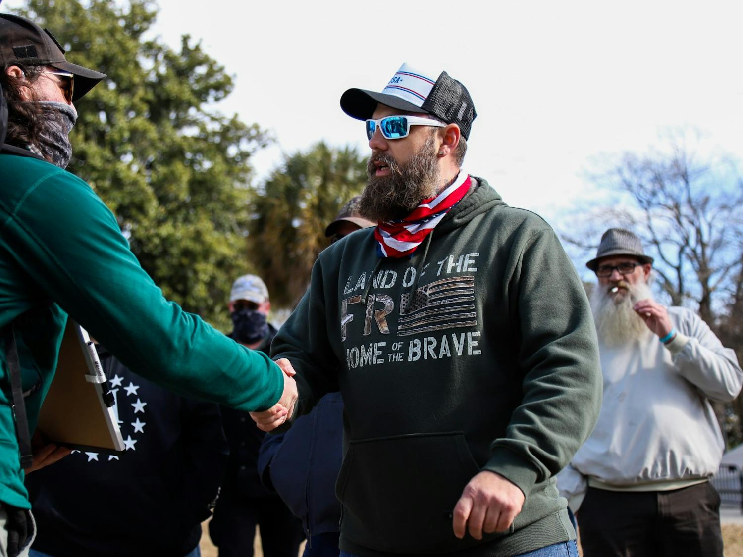 Shawn Laurie of the “Drive4America” caravan shakes the hand of one of the counter-protesters. Many protesters shook hands after a discussion.&nbsp;
