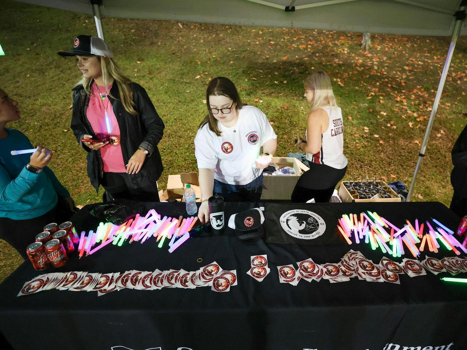 Student workers from Gamecock Entertainment place glowsticks and stickers on a table before Tiger Burn on Nov. 20, 2024. Attendees could grab a glow stick and soda before heading out to the field.